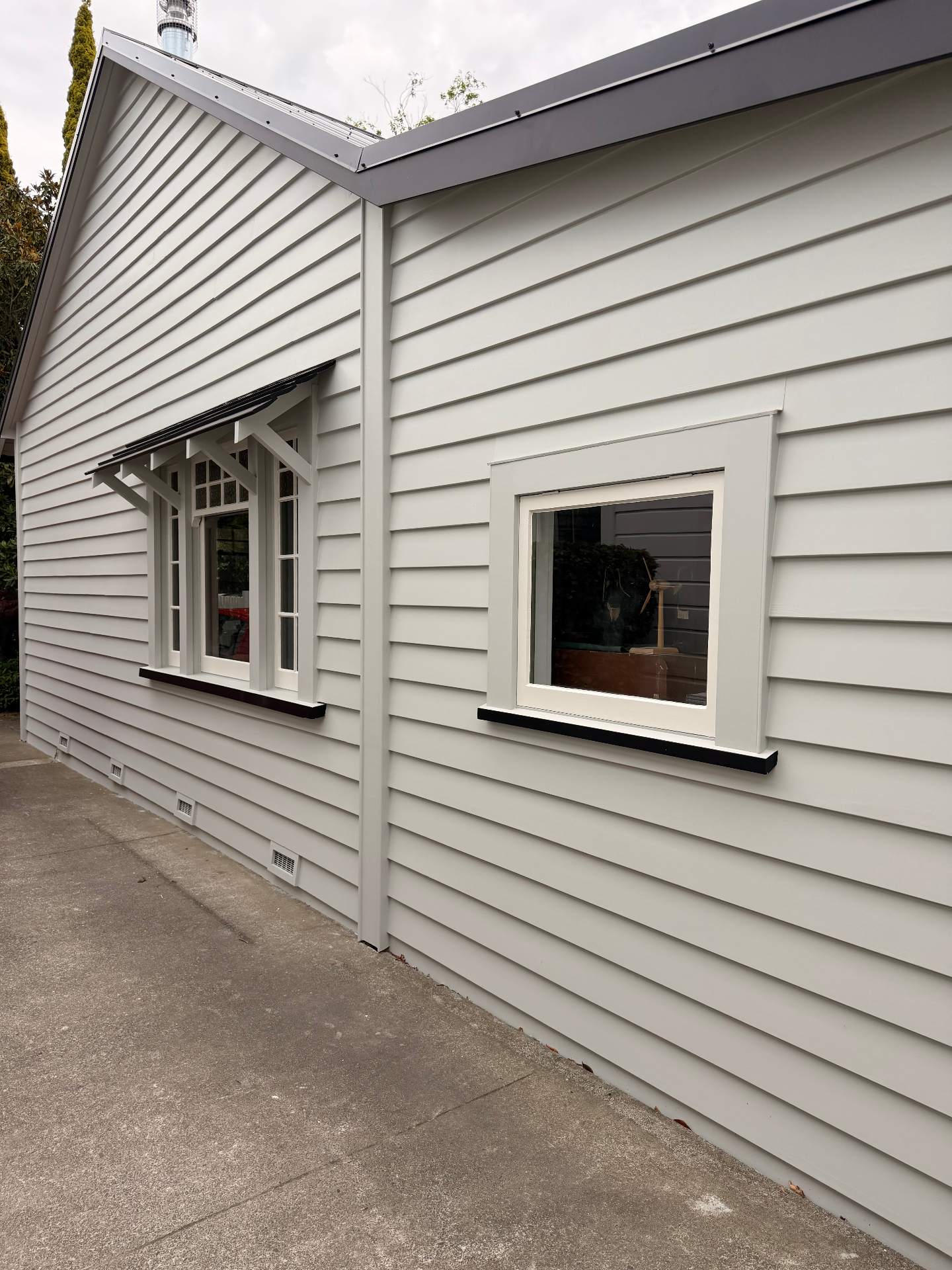Soft grey weatherboard exterior with crisp white window joinery