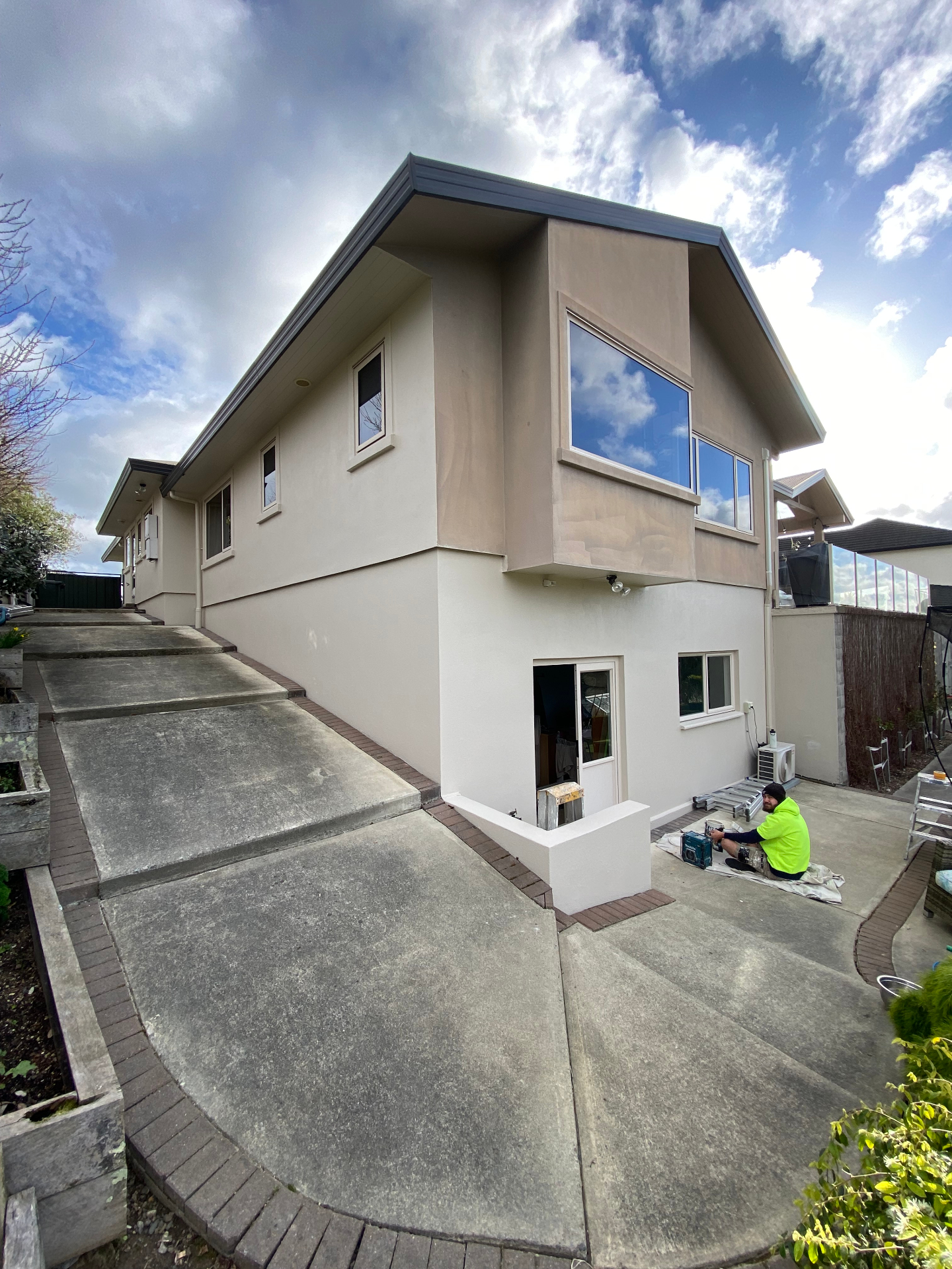 Two-tone plaster exterior repaint in warm neutral tones